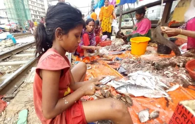 কাওরান বাজার সংলগ্ন রেললাইনের পাশে মাছ কাটছে শিশুরা