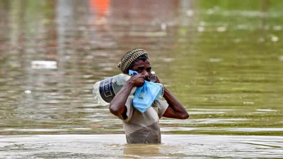 বন্যার পানির মধ্যে দিয়ে খাবার পানি এবং ত্রাণ সামগ্রী নিয়ে যাচ্ছেন একজন ব্যক্তি। ছবিটি ২০২৪ সালের ২৪ আগস্ট ফেনী থেকে তোলা/এএফপি