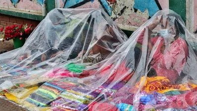 বৃষ্টি থেকে নিজেদের মালামাল রক্ষা করতে পলিথিনের সাহায্য নিয়েছেন তিনজন হকার। ঢাকার শিশু হাসপাতালের সামনে থেকে ছবিটি তোলা/ঢাকা ট্রিবিউন